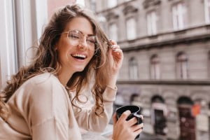 woman smiling in front of window with a cup of coffee