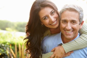 husband and wife embrace outside smiling at the camera